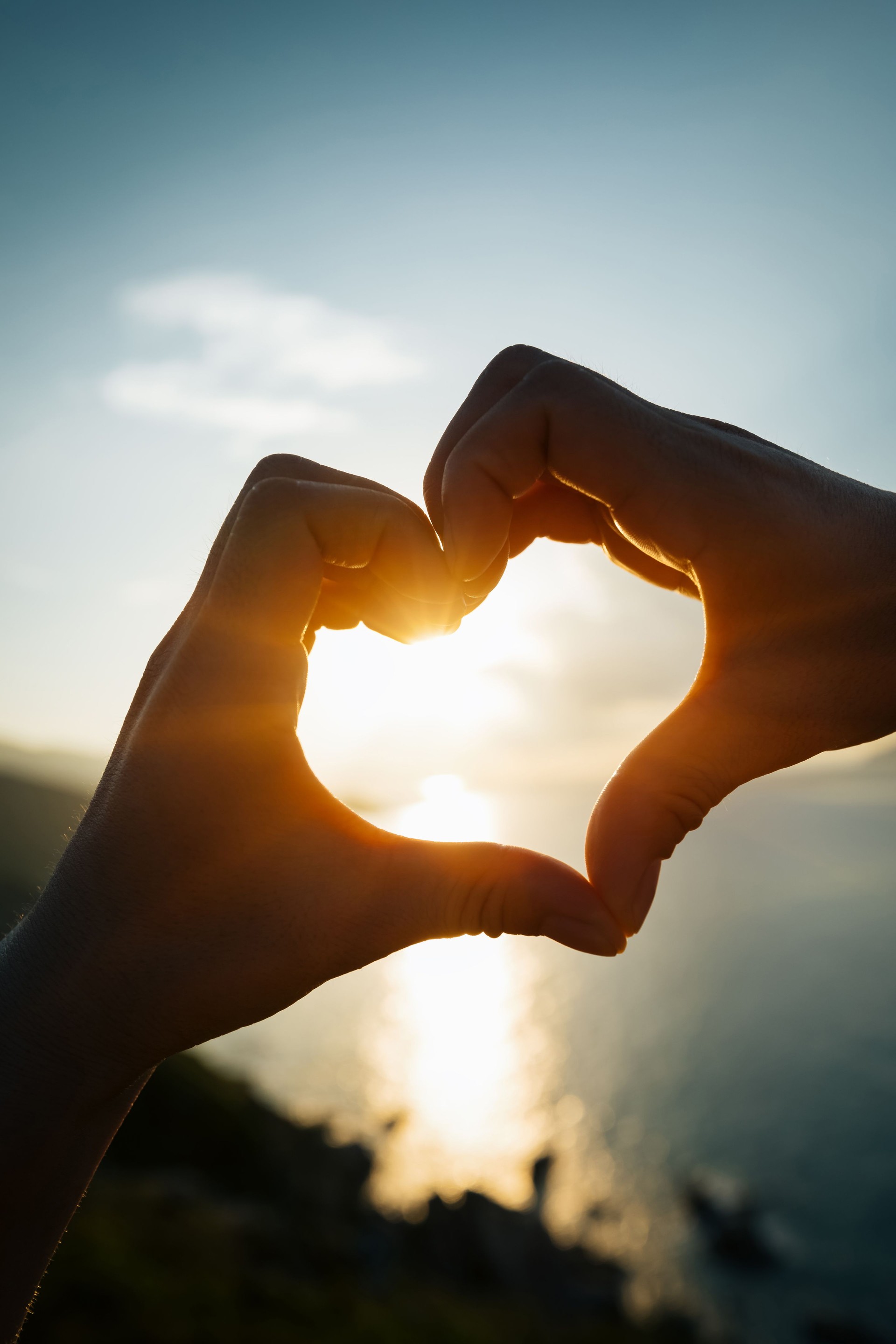 Two hands making heart shape in sky